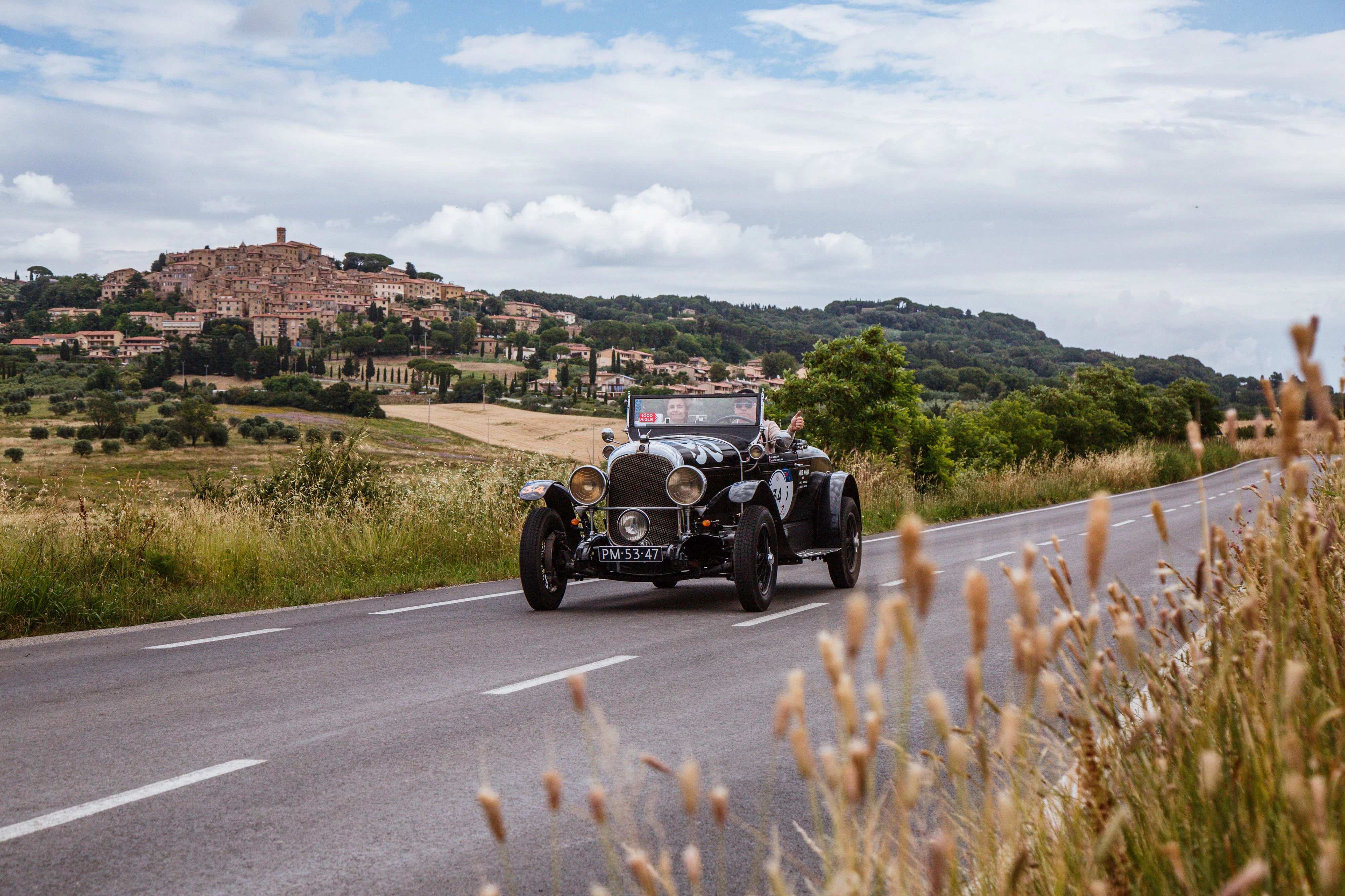 Ein Chrysler 72, Baujahr 1928, während der Mille Miglia 2024: Unterwegs in der Maremma, im Hintergrund der mittelalterliche Ort Casale Marittimo.