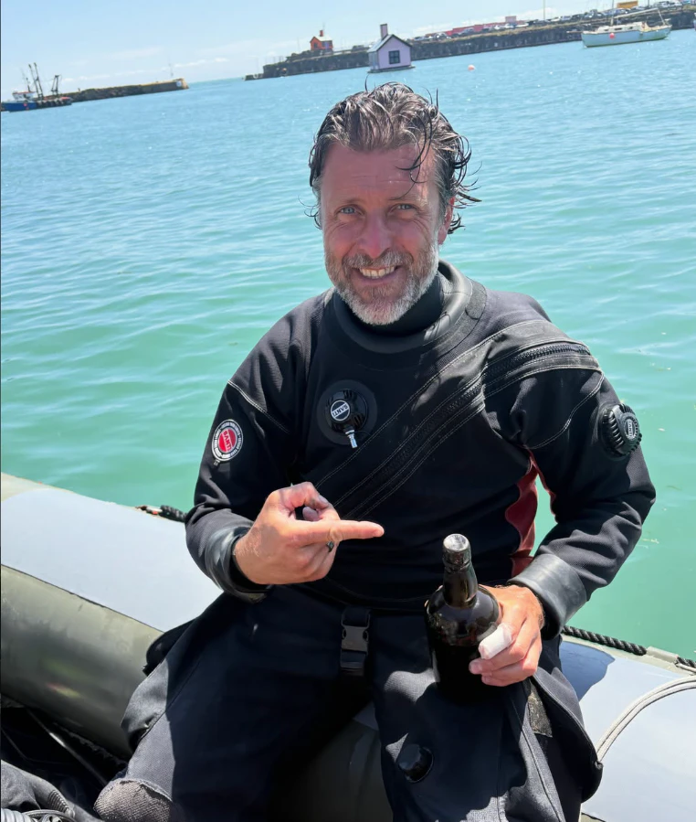 Stefan Panis mit seiner im Meer gefundenen Guinness-Flasche.